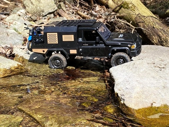 Čierne RC auto Toyota Land Cruiser prechádza potokom